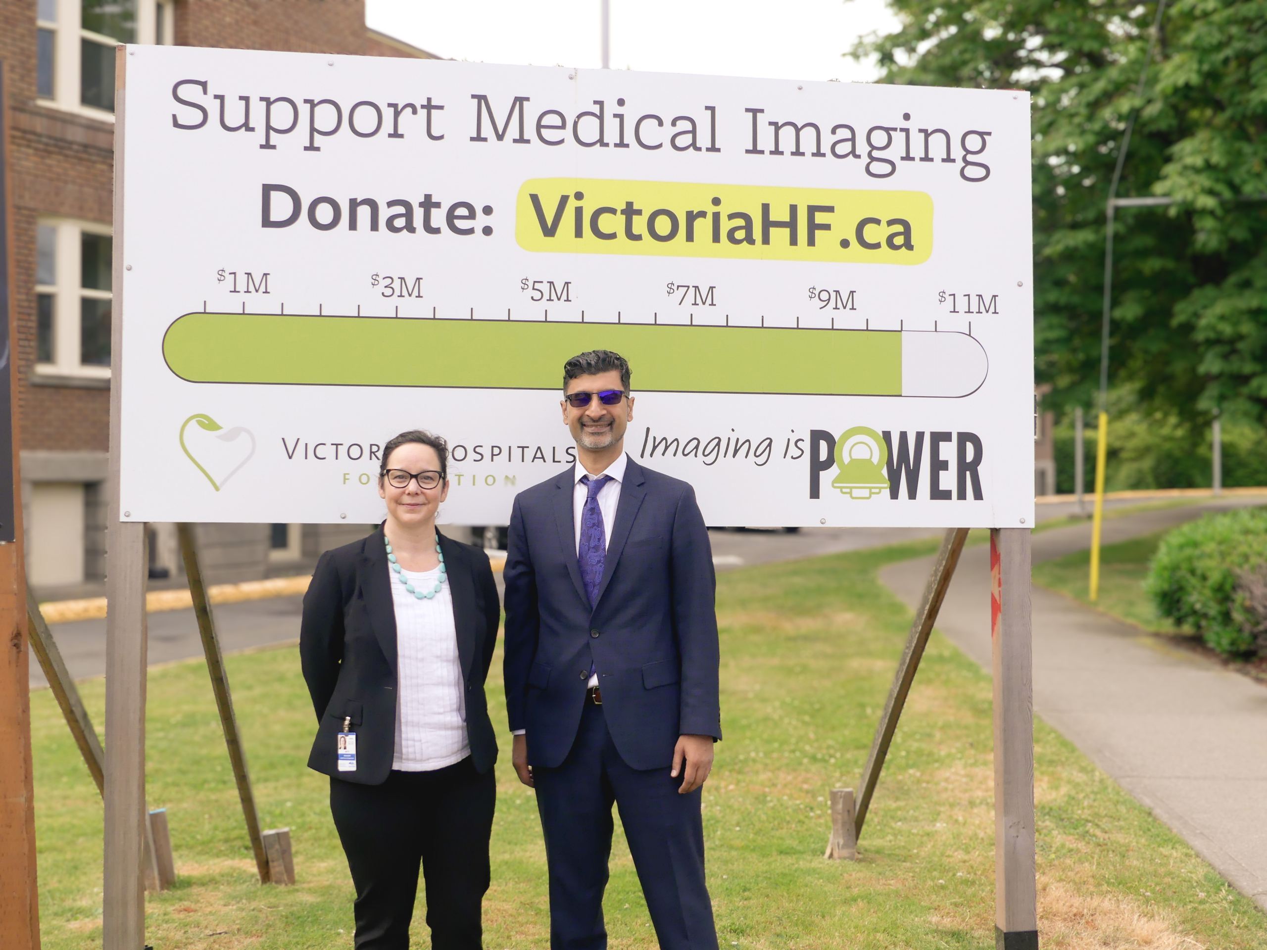 A representative from VHF & Canada Life stand together in front of the Imaging is Power Campaign thermometer sign, now showing $10 million raised