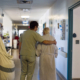 Nurse and elderly woman walking down hospital hallway together