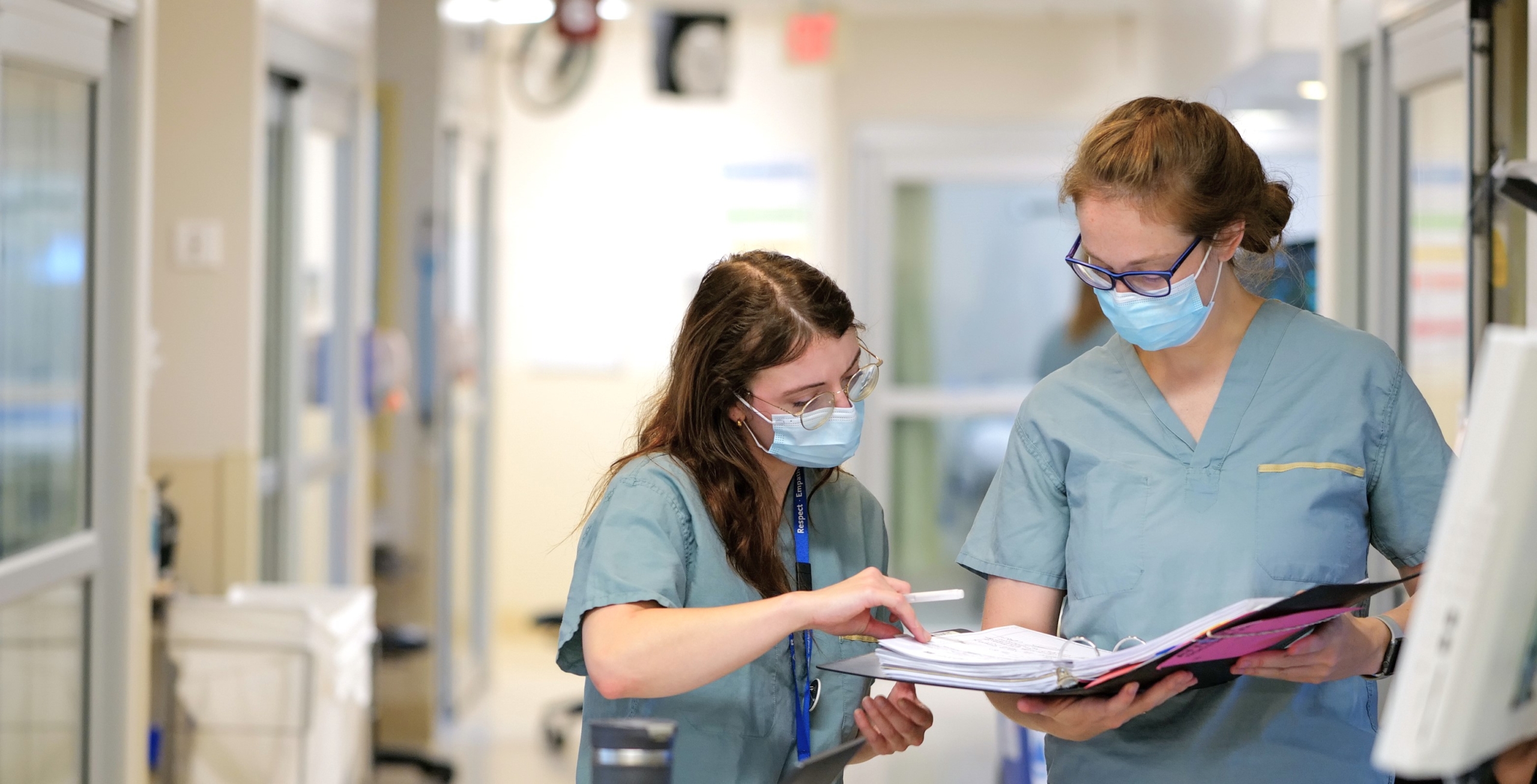 Two caregivers study a binder of medical information